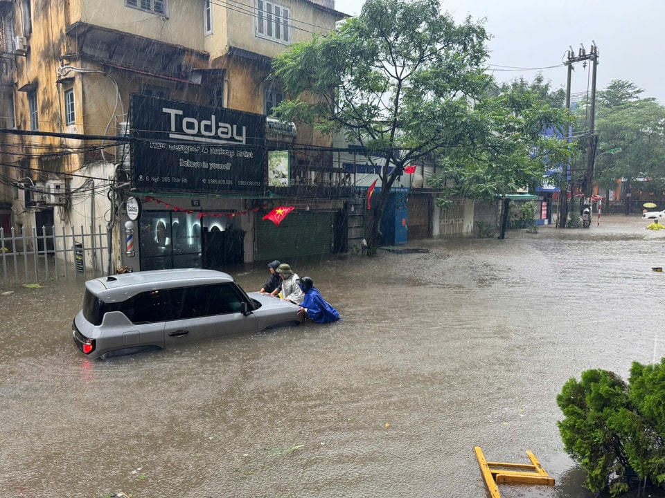 Người dân cố gắng đẩy phương tiện chết máy tới chỗ cao ráo hơn. (Ảnh: Hoài Nam/Vietnam+)