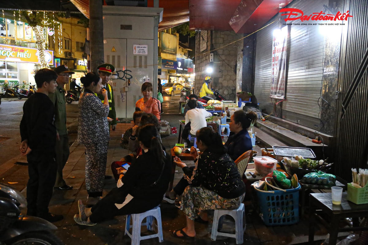 Lực lượng chức năng yêu cầu người dân thu gọn đồ đạc không lấn chiếm vỉa hè.