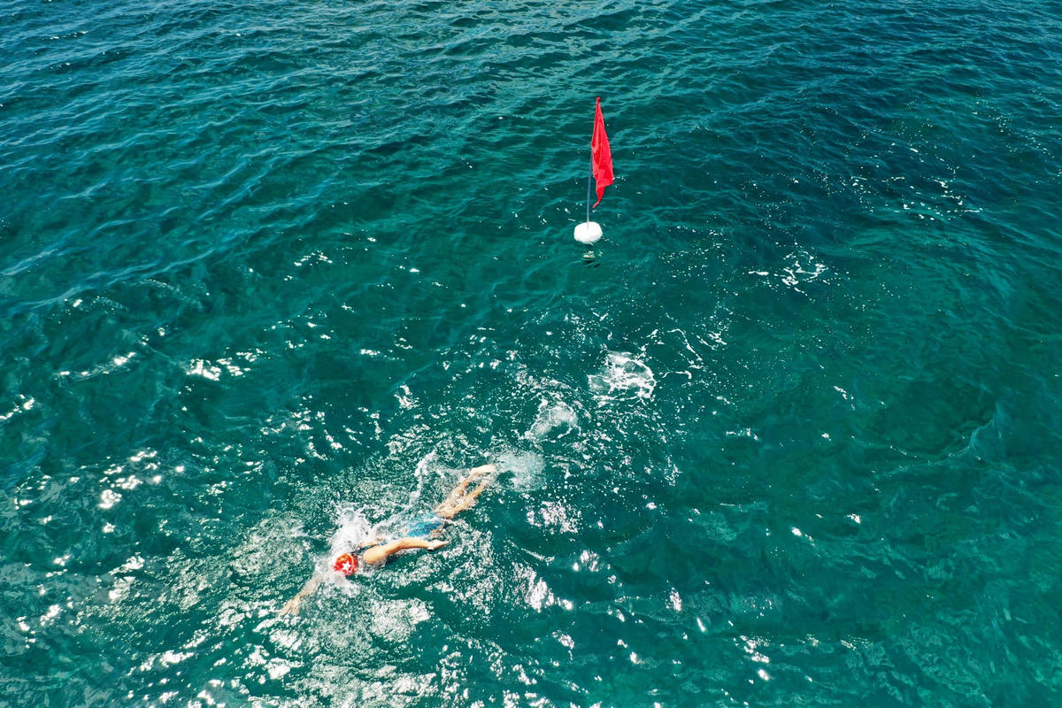 VĐV bơi trong nước biển trong xanh.