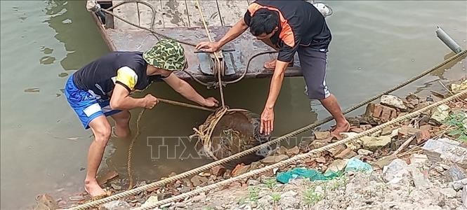 Lực lượng chức năng tiến hành trục vớt quả bom trên sông Đuống. Ảnh TTXVN phát.
