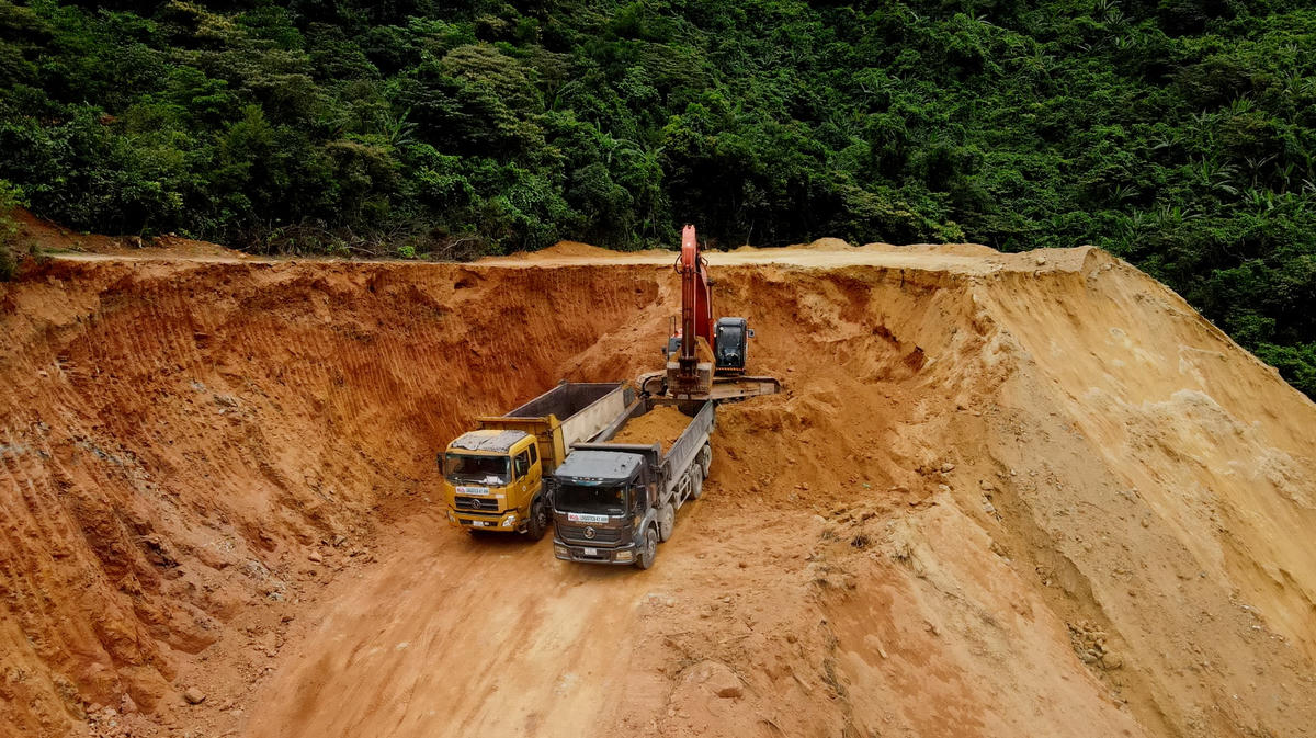 Chiếc máy xúc đang cung cấp đất cho các xe tải.