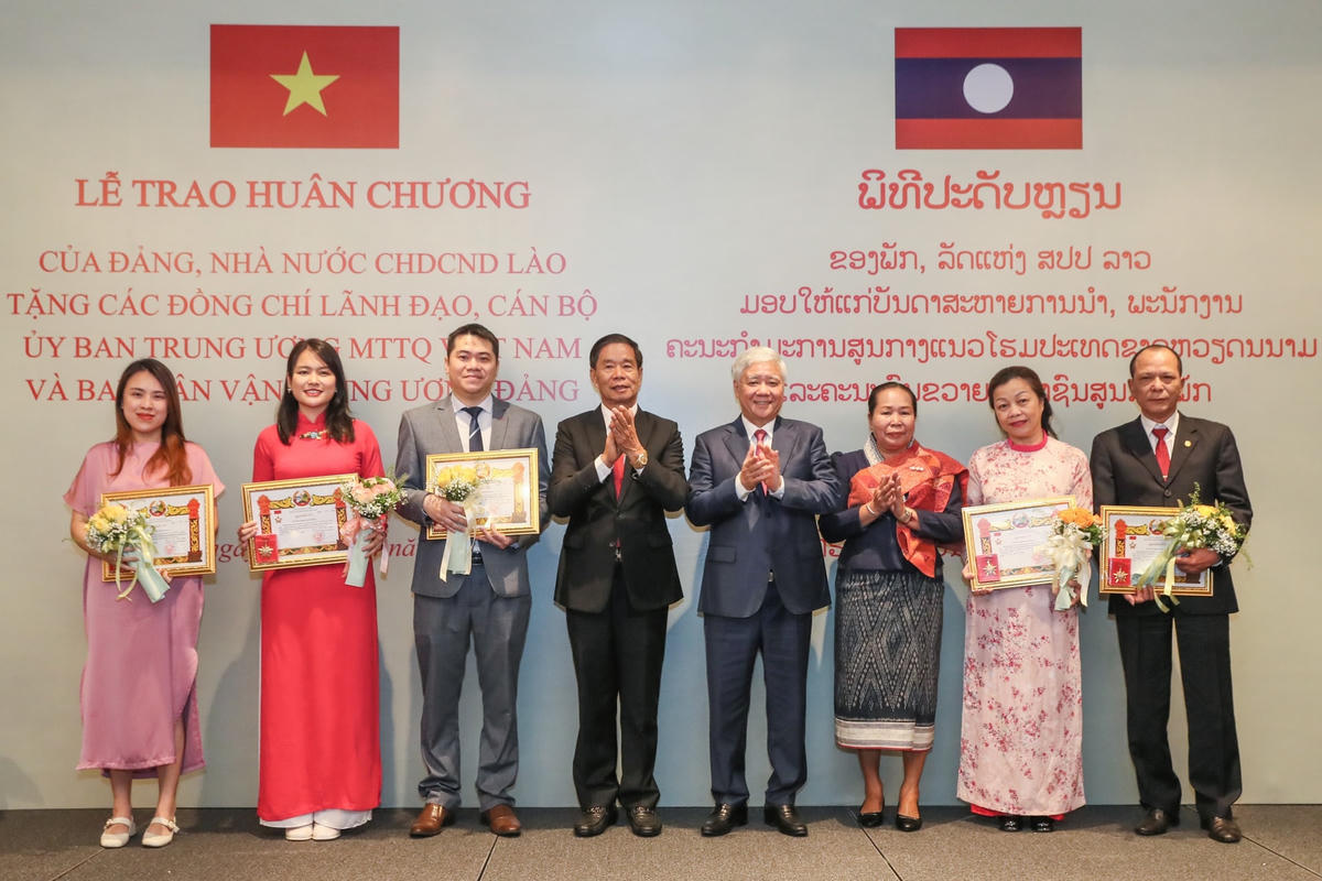 Chủ tịch Uỷ ban Trung ương Mặt trận Lào xây dựng đất nước Sinlavong Khoutphaythoune và Chủ tịch Uỷ ban Trung ương MTTQ Việt Nam Đỗ Văn Chiến chụp ảnh lưu niệm với các cá nhân được trao tặng Kỷ niệm chương của Trung ương Mặt trận Lào xây dựng đất nước.