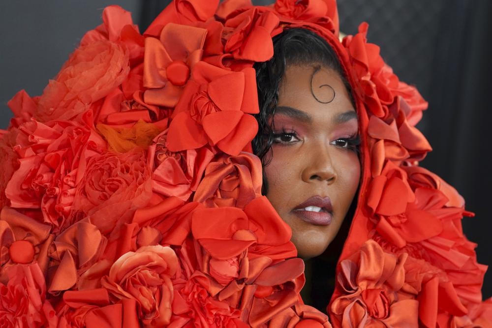 Lizzo gây ấn tượng mạnh trong chiếc áo khoác opera Dolce & Gabbana màu cam sáng được trang trí bằng hoa và chiếc mũ trùm đầu khổng lồ khi bước đi trên thảm đỏ Grammys ngày 5/2. Ảnh: AP.
