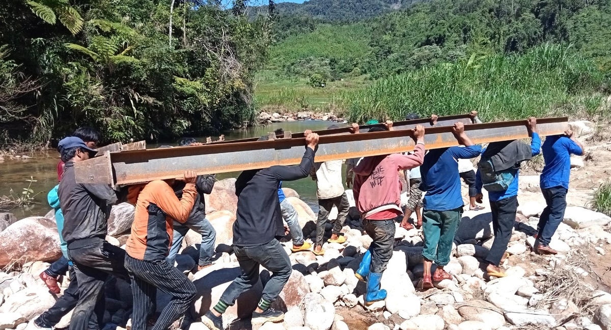 Thanh niên vận chuyển vật liệu dưới trời nắng để làm cầu.