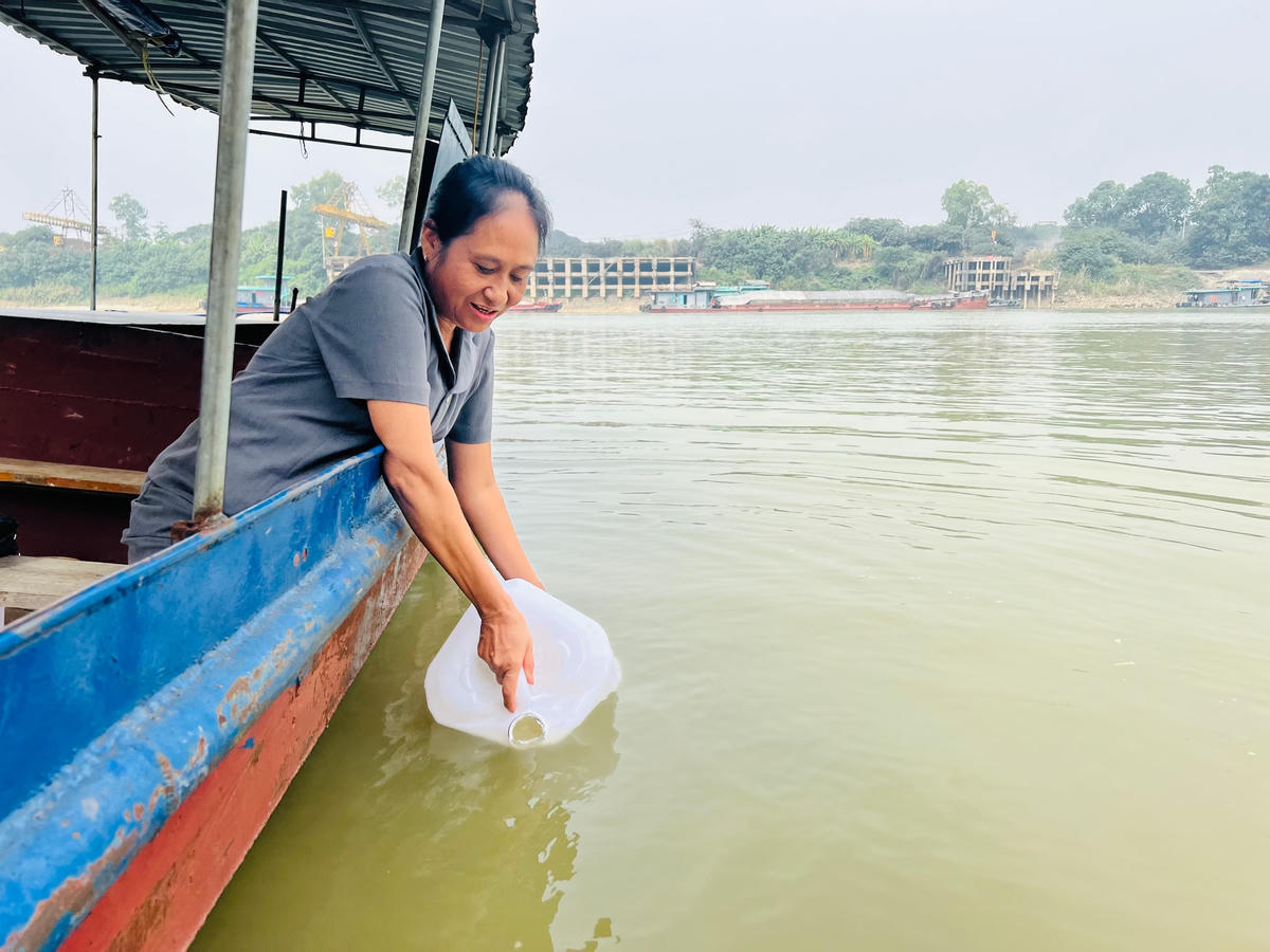 Chị Phan Thị Thơm ở bến ngã ba Hạc lấy “nước thiêng” cho du khách.  