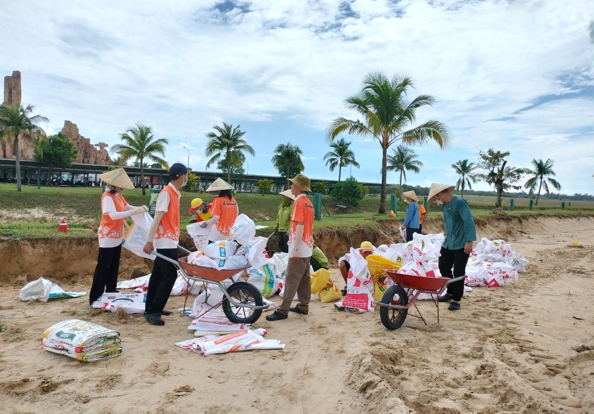Nhân viên công ty xúc cát vào bao để chằng chống nhà.