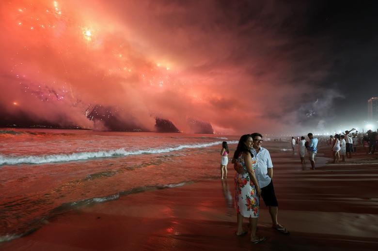 Mọi người ăn mừng dưới bầu trời pháo trong lễ mừng năm mới, tại bãi biển Copacabana, ở Rio de Janeiro, Brazil.