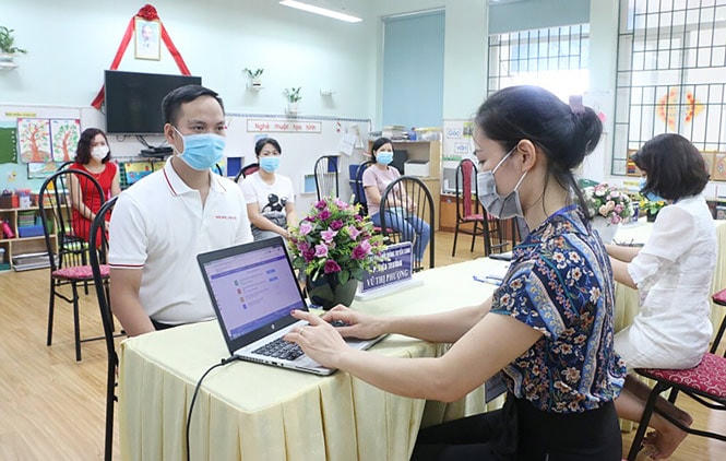Giáo viên hỗ trợ phụ huynh đăng ký tuyển sinh trực tuyến năm học 2020-2021 tại Trường Mầm non Hàng Đào (quận Hà Đông, Hà Nội).  Ảnh: Kim Thỏa