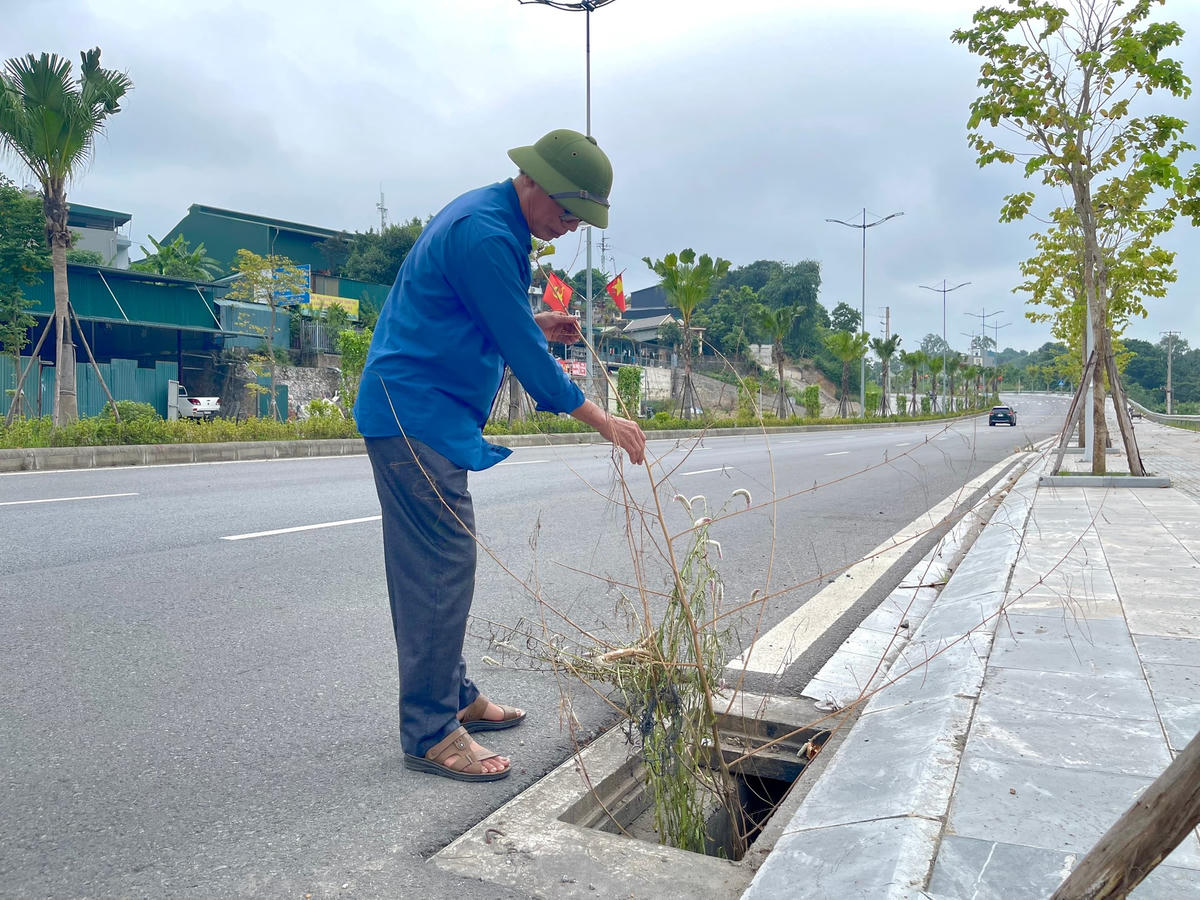 Ông Nguyễn Văn Tiến cắm cành cây khô vào hố ga bị mất nắp để cảnh báo người đi đường.