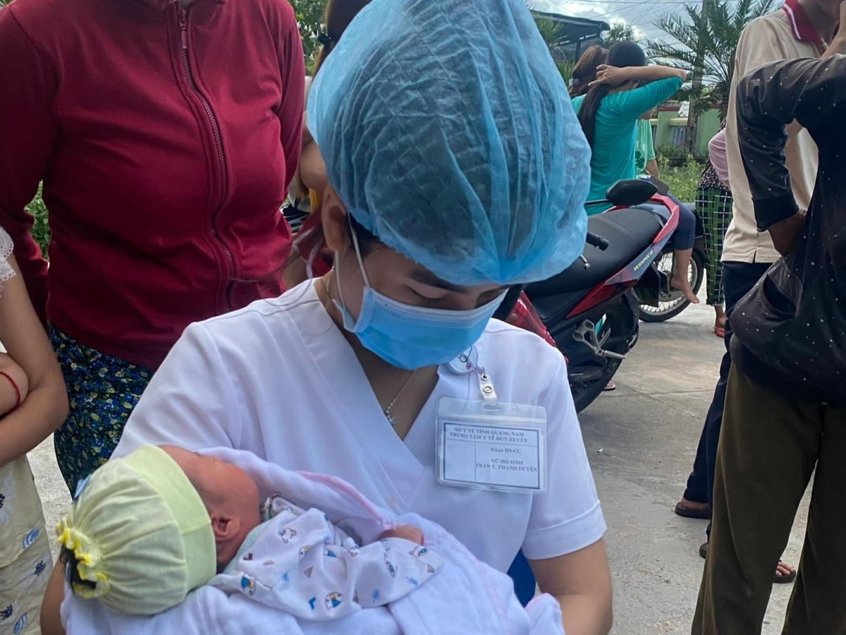 Nhân viên y tế đang bế bé gái bị bỏ rơi ở thôn An Thành. 