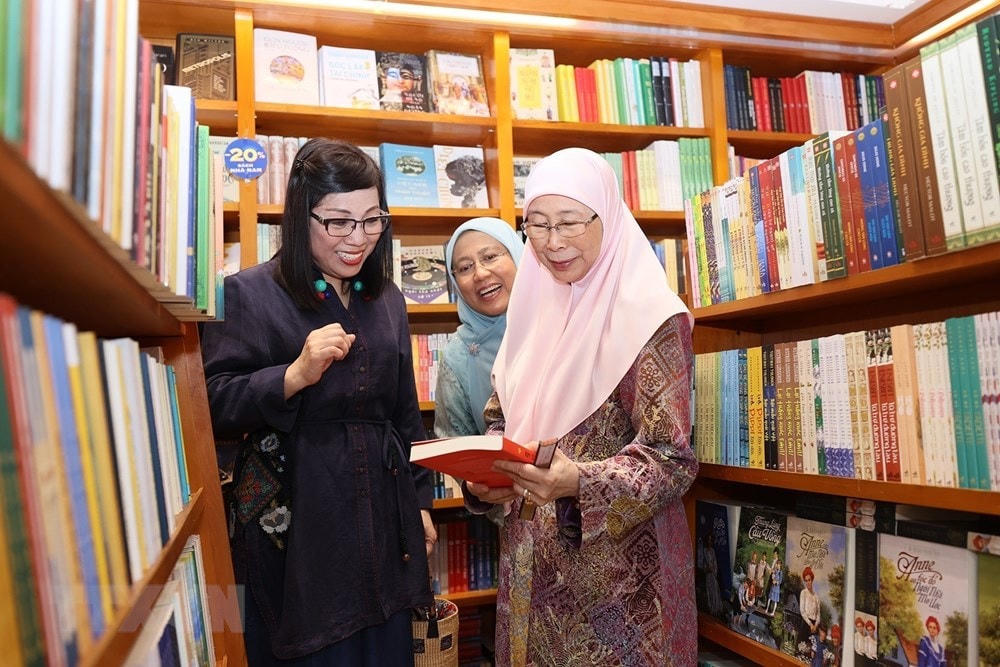 Bà Lê Thị Bích Trân, Phu nhân Thủ tướng Phạm Minh Chính và bà Dato’ Seri Dr. Wan Azizah binti Dr. Wan Ismail, Phu nhân Thủ tướng Anwar Ibrahim xem sách. (Ảnh: Dương Giang/TTXVN).