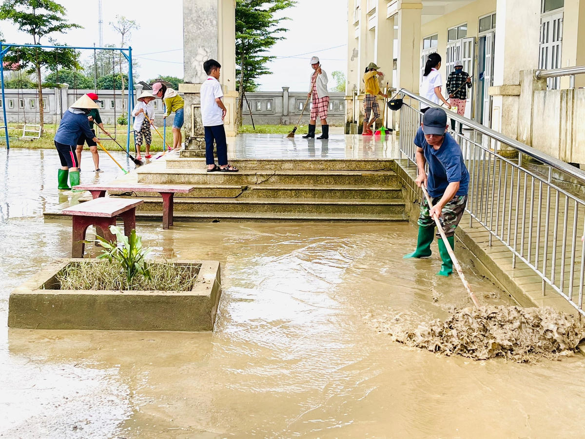 Người dân hỗ trợ giáo viên dọn dẹp khuôn viên trường học sau mưa lũ.