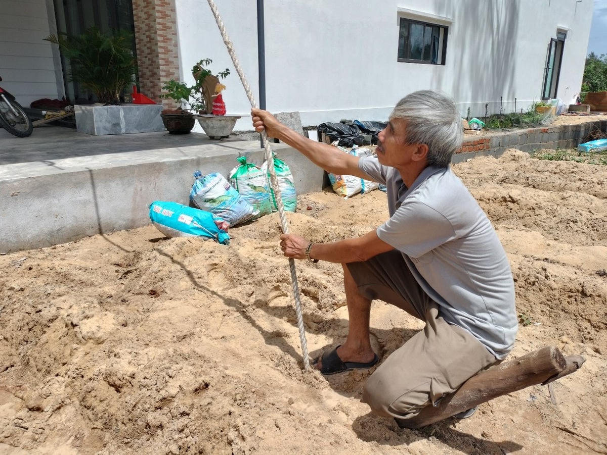 Ông Nguyễn Văn Trung cột dây thừng giữ mái nhà cố định.