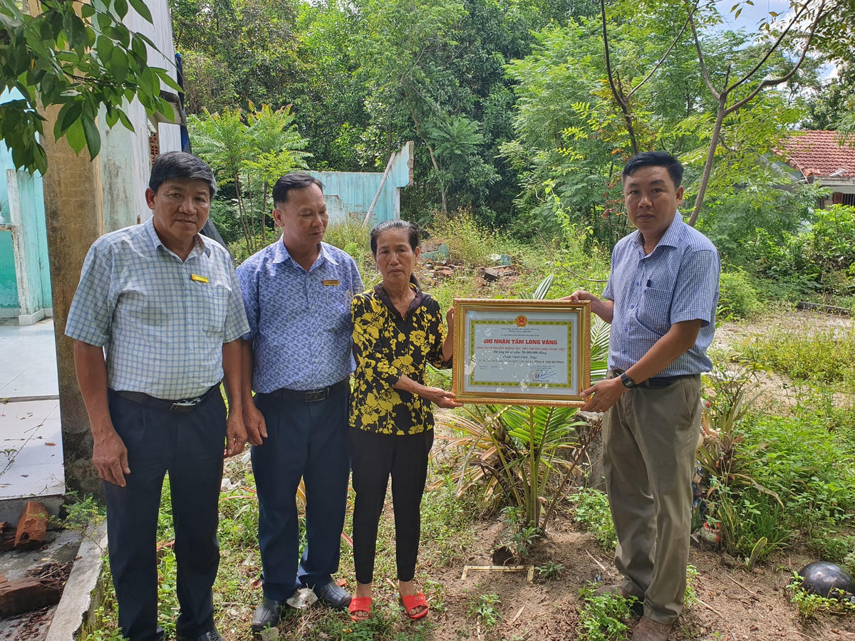 Người nhà nhận bảng tượng trưng hỗ trợ tiền xây dựng nhà cho cụ Hương do lãnh đạo phường trao.