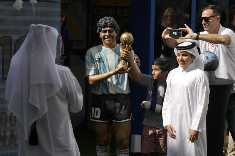 Các cổ động viên tại thành phố Doha của Qatar bên cạnh bức tượng Maradona.
