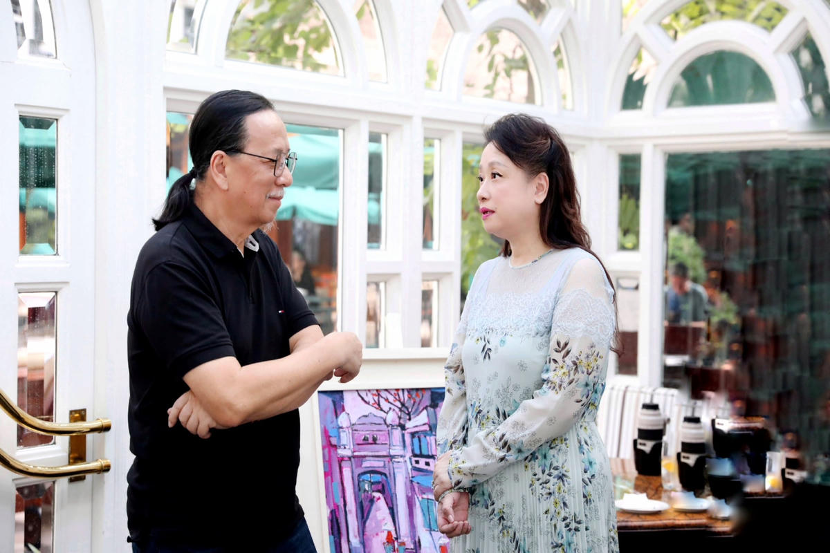 Nhà sưu tập Thúy Anh trò chuyện cùng họa sĩ Phạm Luận.