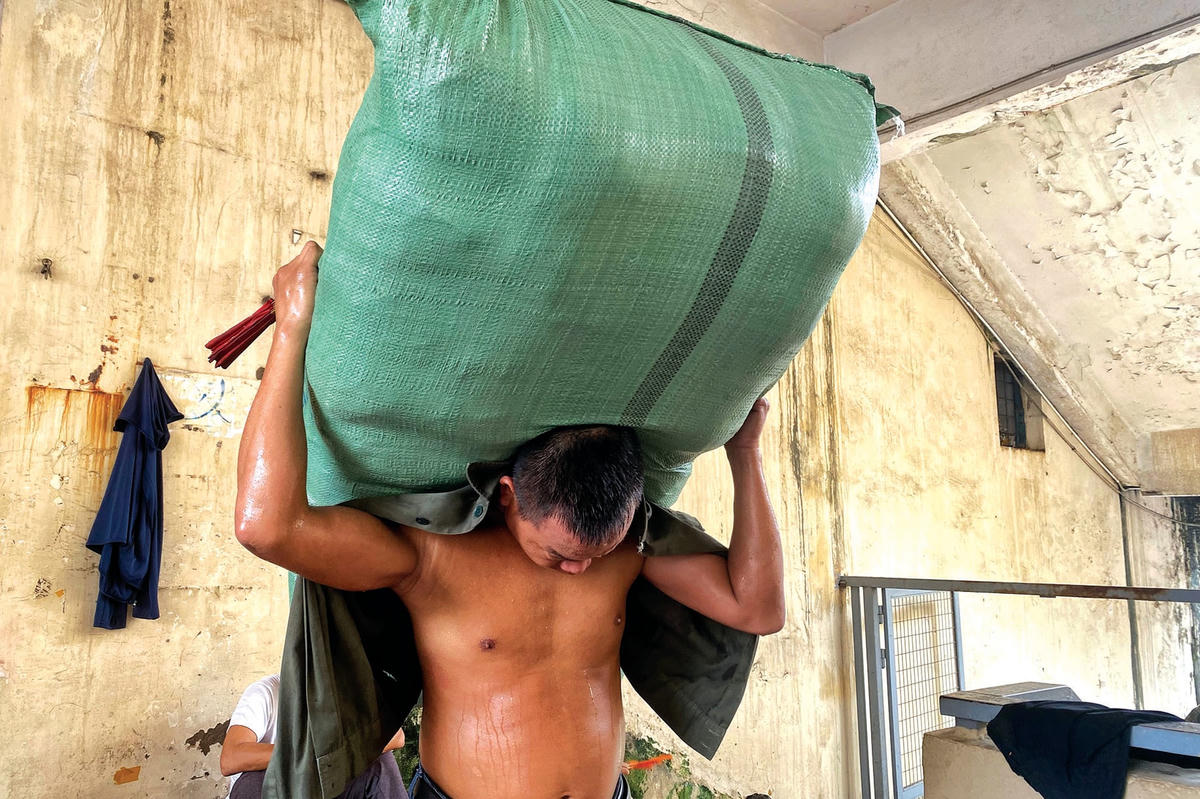 Người đàn ông khuân bao hàng nặng khoảng 100 kg di chuyển từ tầng 1 lên tầng 3 của khu chợ.  