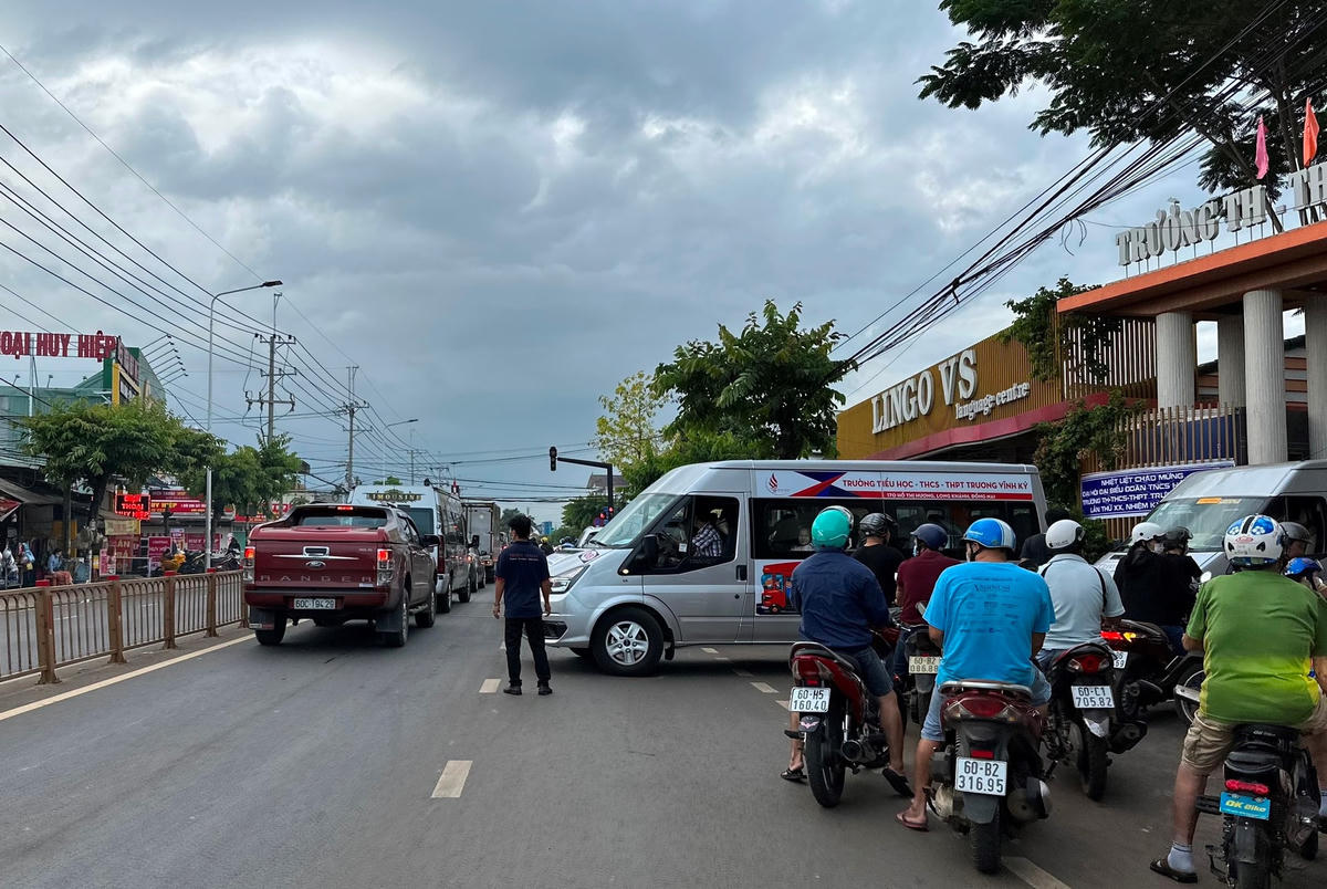 Trường TH-THCS-THPT Trương Vĩnh Ký cho người chặn đường để xe đưa đón học sinh ra cổng, trong khi đó lực lượng chức năng thì "lặn" mất tăm. Ảnh: Mạnh Thìn.