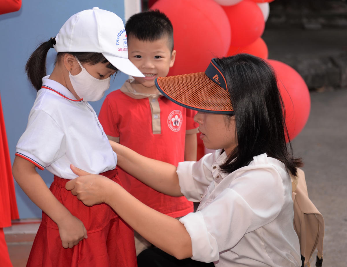 Phụ huynh ân cần hỏi han, chỉnh trang đồng phục cho con trước khi dự lễ khai giảng.