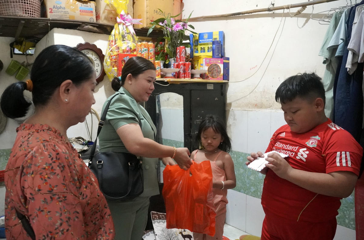Chủ tịch UBND phường Thắng Nhì tặng quà và lì xì cho hai cháu của bà Mai tại phòng trọ chiều 28/1. Ảnh: Đông Hà/Tuổi Trẻ.