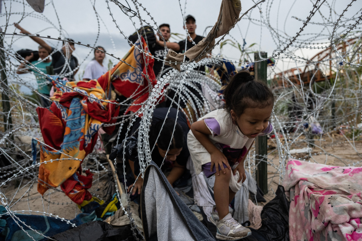 Một em bé cố chui qua hàng rào thép gai từ Mexico vào Mỹ. Nguồn: New York Post.