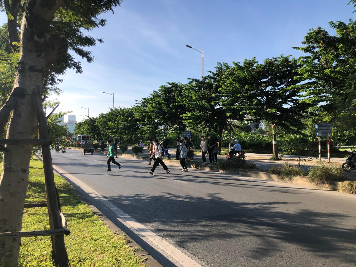 Từng tốp người đi bộ băng qua đường trong thời điểm phương tiện lưu thông đông đúc với tốc độ cao.