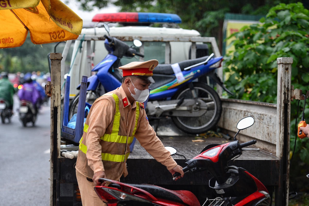 Lực lượng chức năng đưa xe máy vi phạm về bãi đỗ xe.