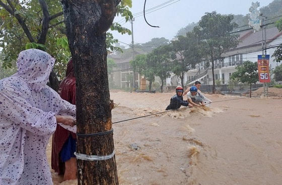 Lực lượng chức năng dùng dây thừng để hỗ trợ "giải cứu" người đàn ông bị mắc kẹt giữa điểm ngập lụt ven biển phường Ghềnh Ráng, TP Quy Nhơn.
