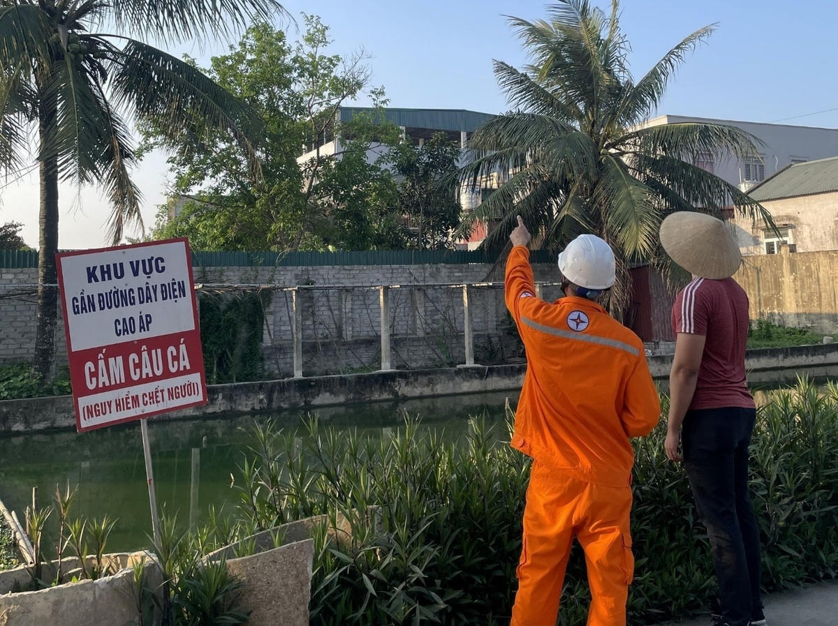 Công nhân Điện lực trực thuộc Công ty Điện lực Thanh Hóa cắm biển cảnh báo và tuyên truyền đến người dân không câu cá tại khu vực gần đường điện cao áp đi qua.