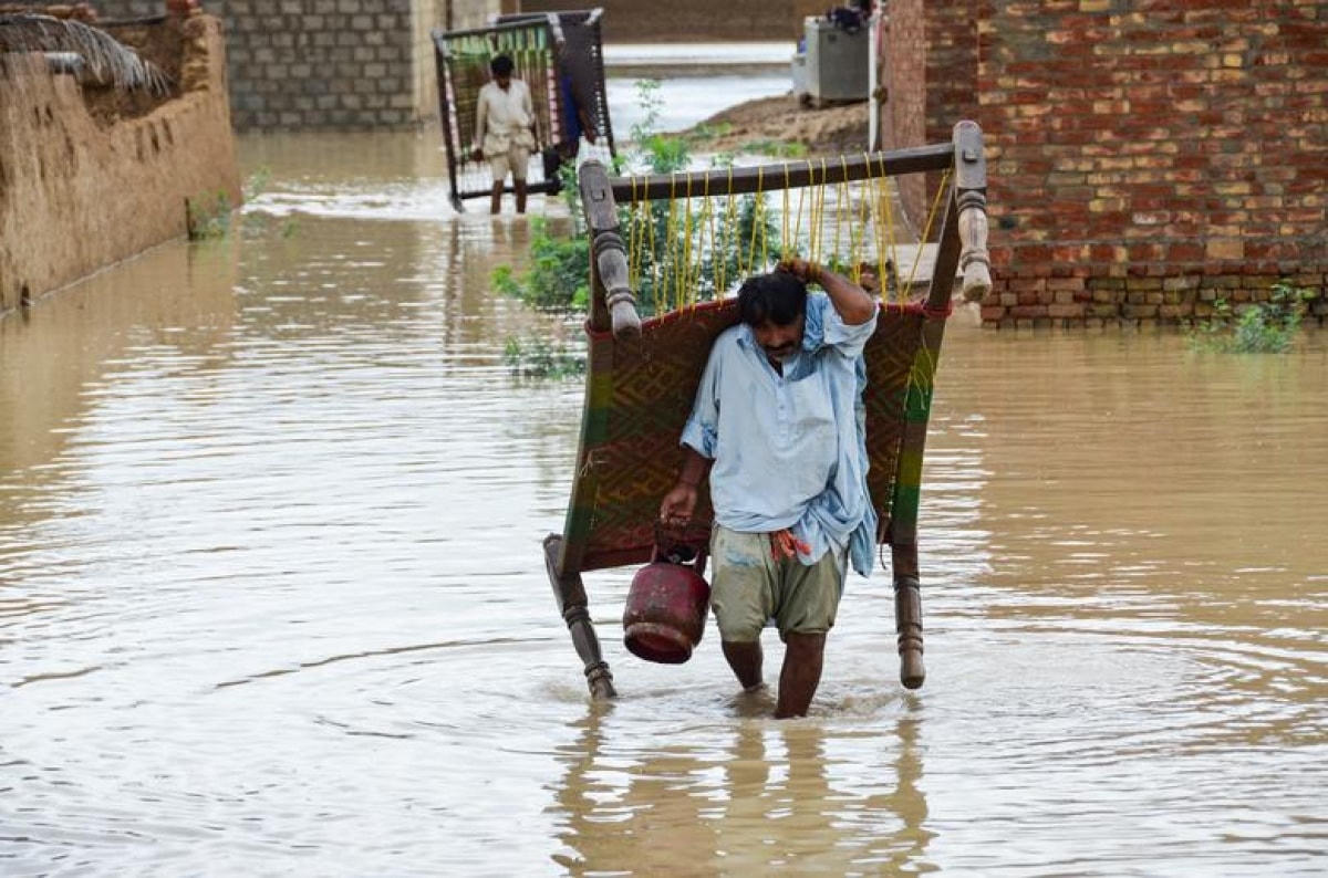 Một người đàn ông ở Dera Yar, Pakistan phải khuân theo chiếc giường chạy lũ.