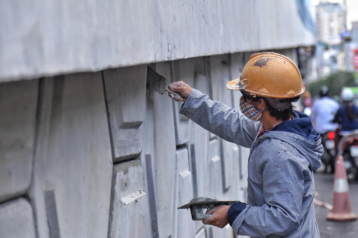 Công nhân đang dùng xi măng lấp kín những khe bêtông dưới chân đường dẫn.