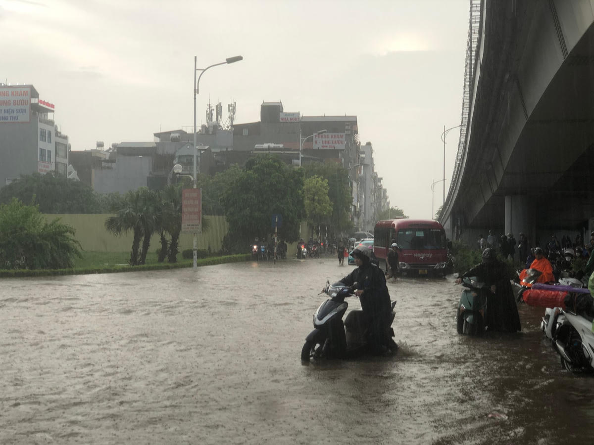 Người dân phải dắt bộ xe máy do đường bị ngập sau mưa lớn. Ảnh: Lê Khánh.