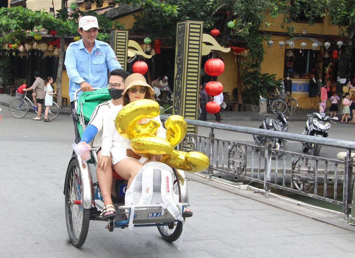 Du khách ngồi xích lô đi qua cầu An Hội.