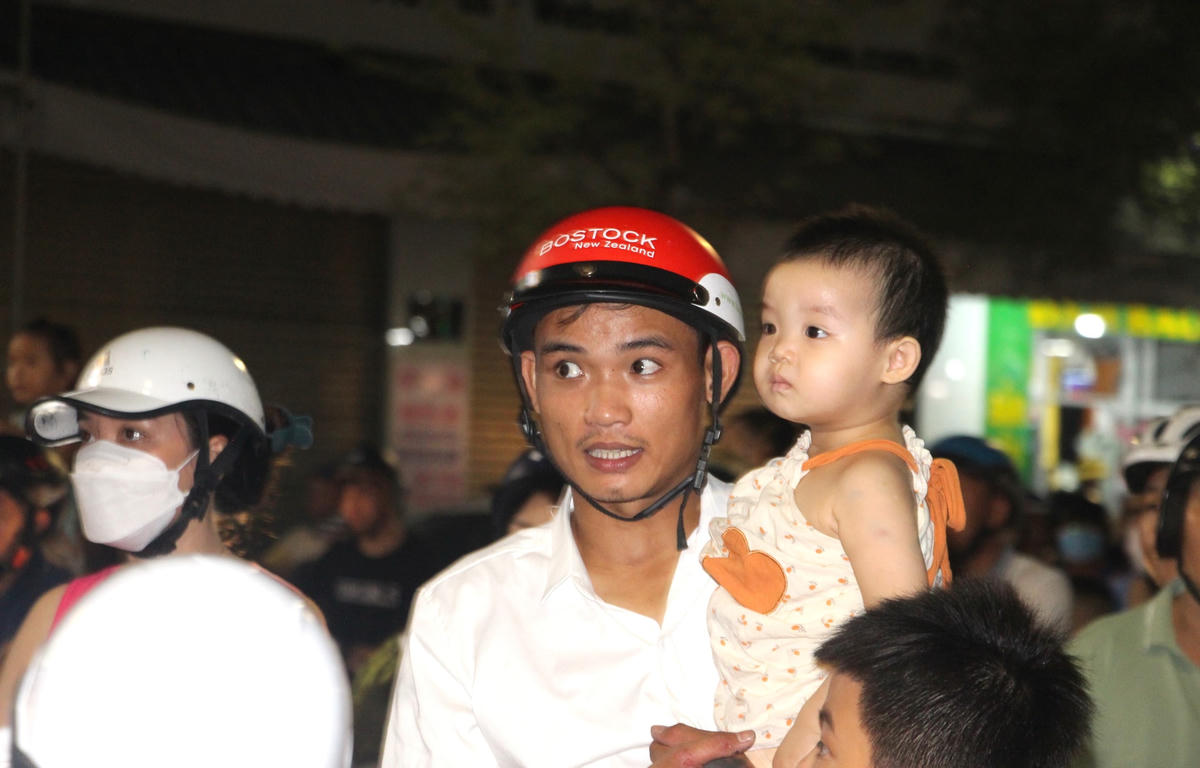 Phụ huynh đưa em nhỏ xem trình diễn múa lân. 