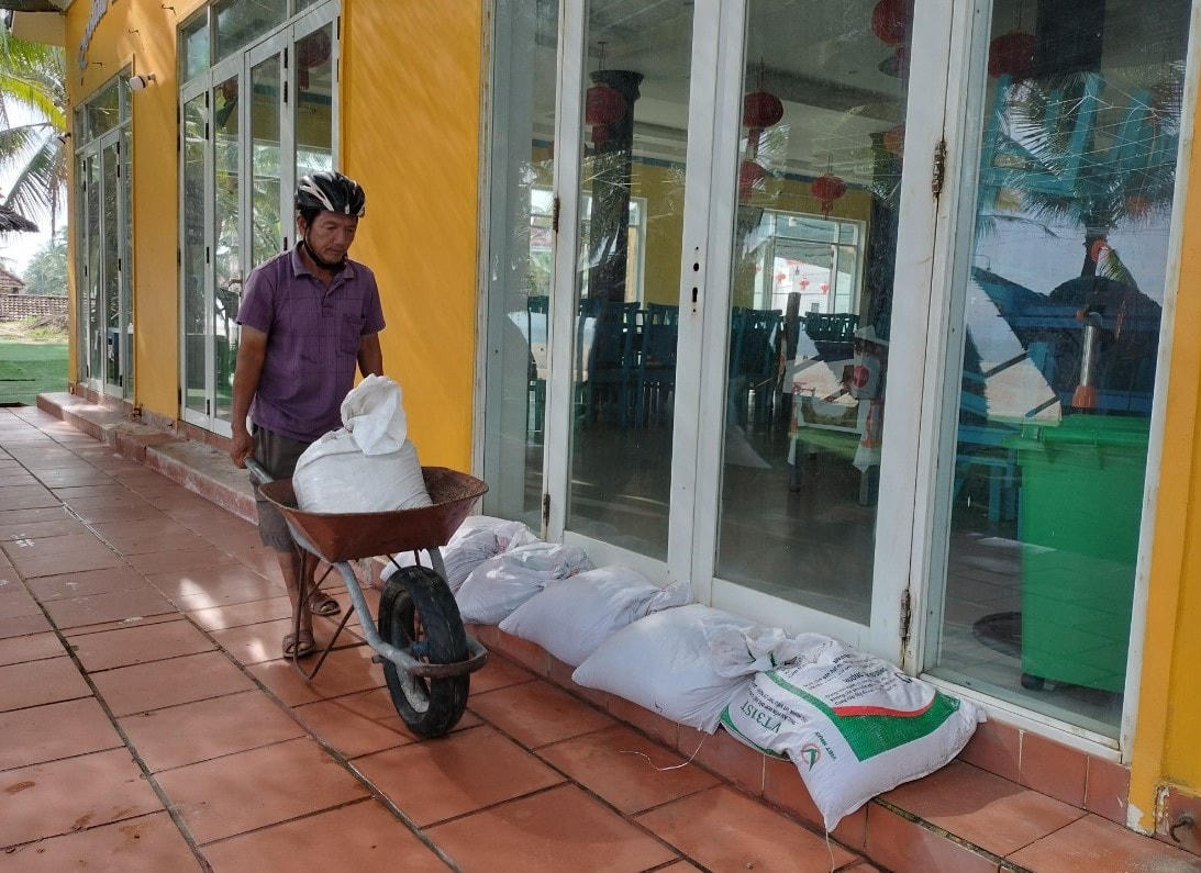 Ông Lê Hưng Thắng đẩy các bao cát để chằng chống cửa, mái nhà.