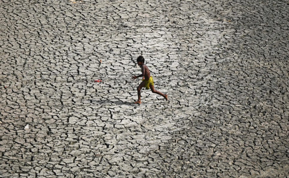 Một cậu bé chạy ngang qua đáy sông khô cằn tại Yamuna. Ảnh: Sajjad Hussain / AFP / Getty Images.