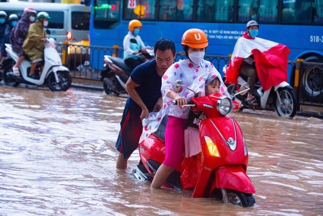 Nước ngập sâu, nhiều phương tiện bị "chết máy". Trong ảnh: Một người dân hỗ trợ "giải cứu" phương tiện bị "chết máy" ra khỏi điểm ngập ở đường Võ Văn Ngân, TP Thủ Đức..