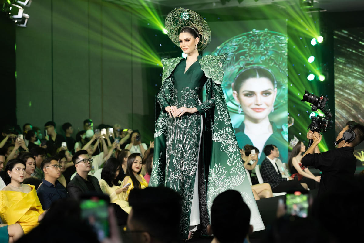 Hoa hậu Isabella Menin làm vedette, mặc thiết kế gắn tà rộng, đầu đội mấn. Cô catwalk trong tiếng reo hò của fan. Người đẹp nói từng biết đến áo dài nhưng nay mới có dịp diện.