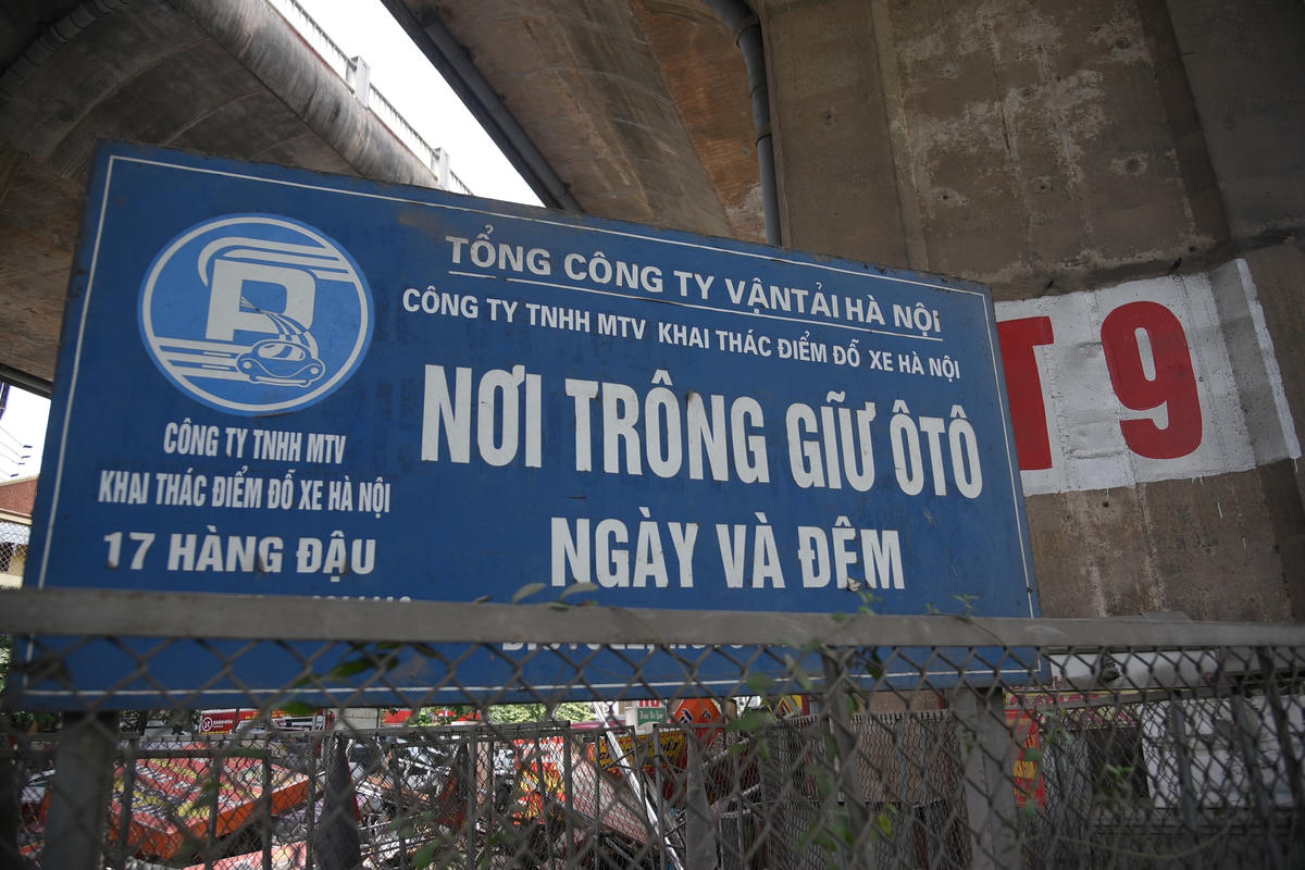 Bãi xe dưới gầm cầu này được quây kín bằng hàng rào lưới sắt. Bên ngoài bãi có cắm biển đơn vị hoạt động trông giữ là Công ty TNHH Khai thác điểm đỗ xe Hà Nội. 