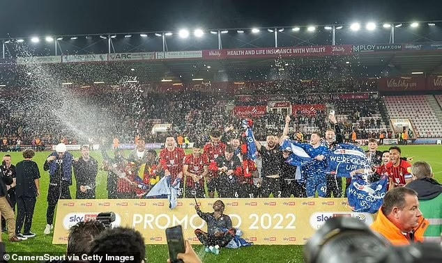 Các cầu thủ Bournemouth bật sâm panh ăn mừng trở lại Premier League sau 3 năm xuống hạng. Mùa trước, Bournemouth cũng đã tham dự vòng play-off tranh vé lên hạng Premier League nhưng thất bại trước Brentford.