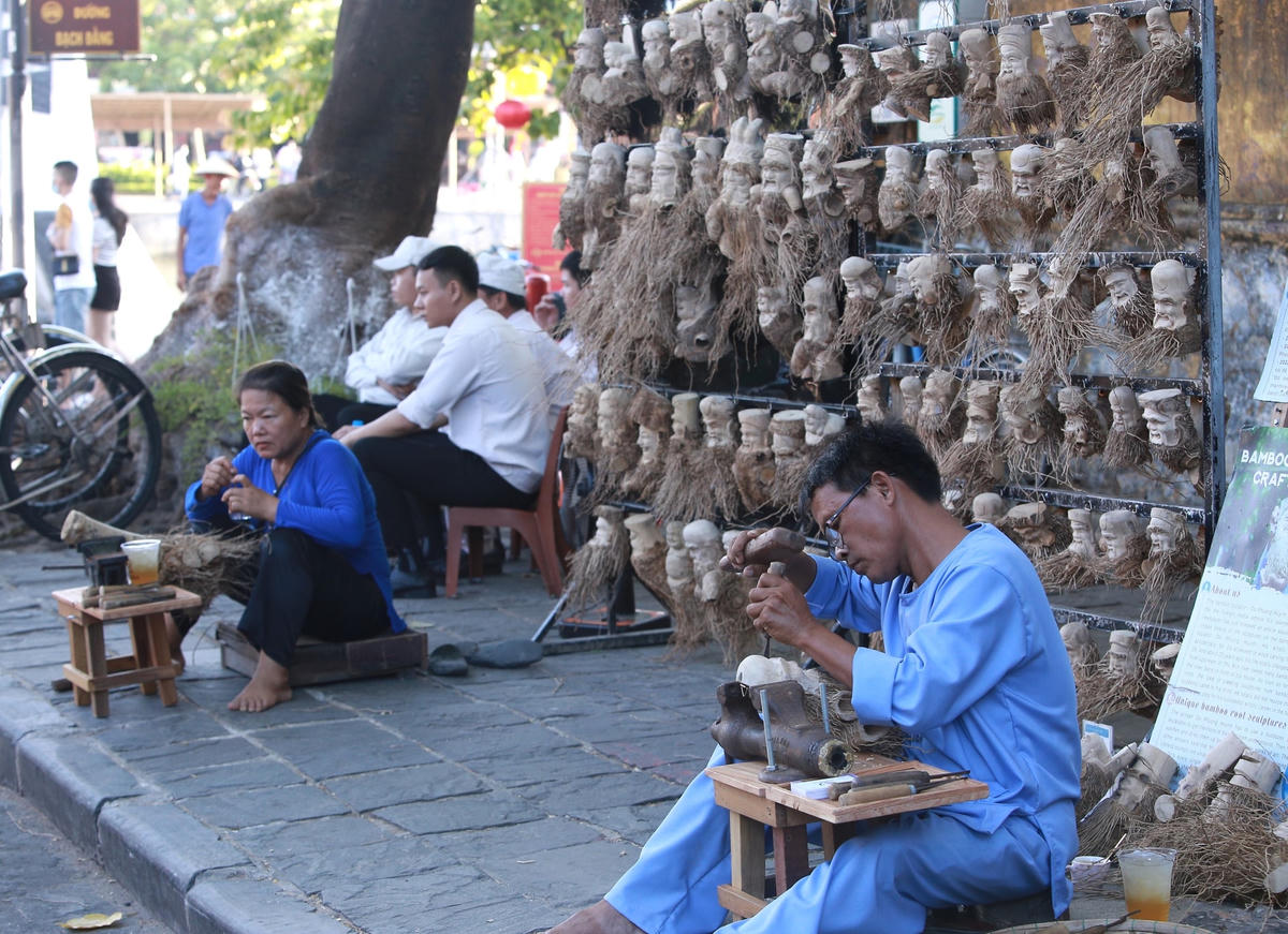 Anh Đỏ ngồi điêu khắc các gốc tre thành những tác phẩm có hòn độc đáo.