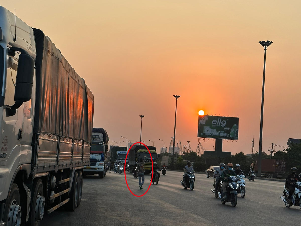 Bất chấp hiểm nguy, những người bán cơm vẫy khách giữa dòng xe ken đặc (Khoanh đỏ). Ảnh: Mạnh Thìn.