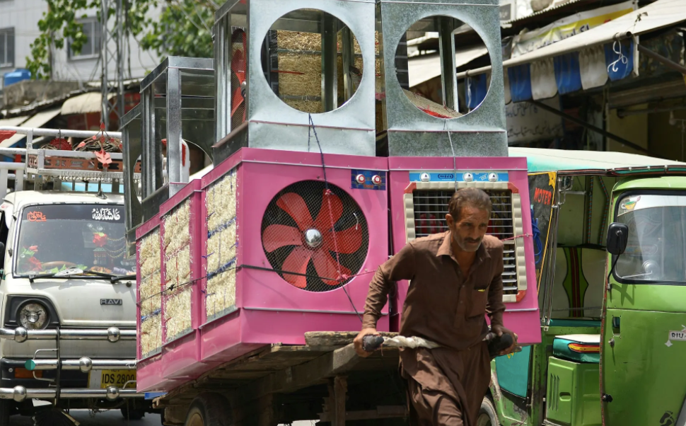 Một người lao động kéo một chiếc xe đẩy tay chất đầy máy làm mát không khí. Ảnh: Farooq Naeem / AFP / Getty Images.