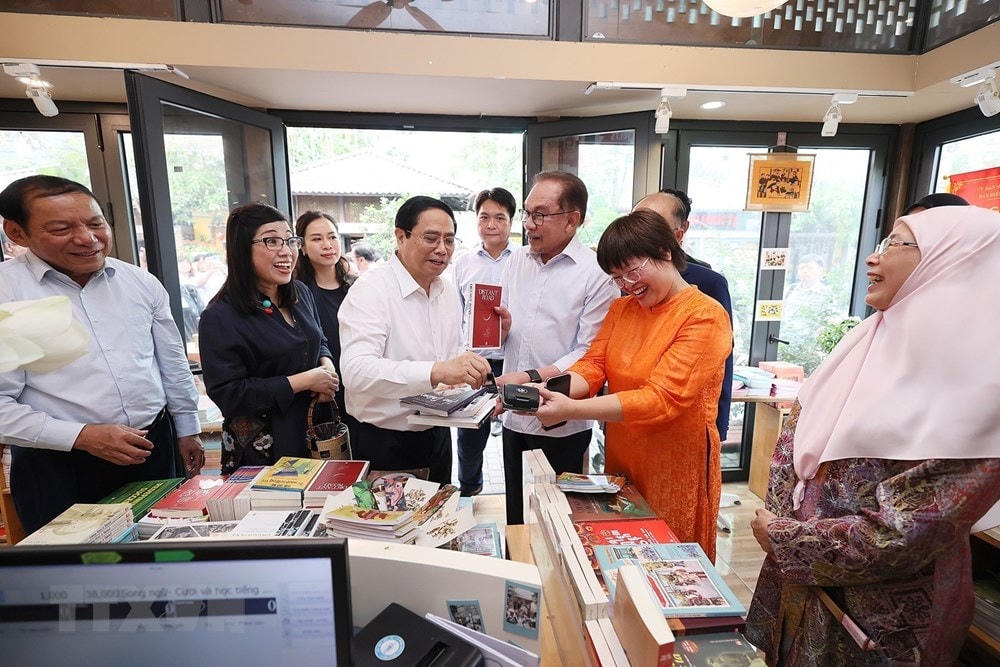 Thủ tướng Phạm Minh Chính mua sách tặng Thủ tướng Malaysia Anwar Ibrahim và Phu nhân. (Ảnh: Dương Giang/TTXVN).