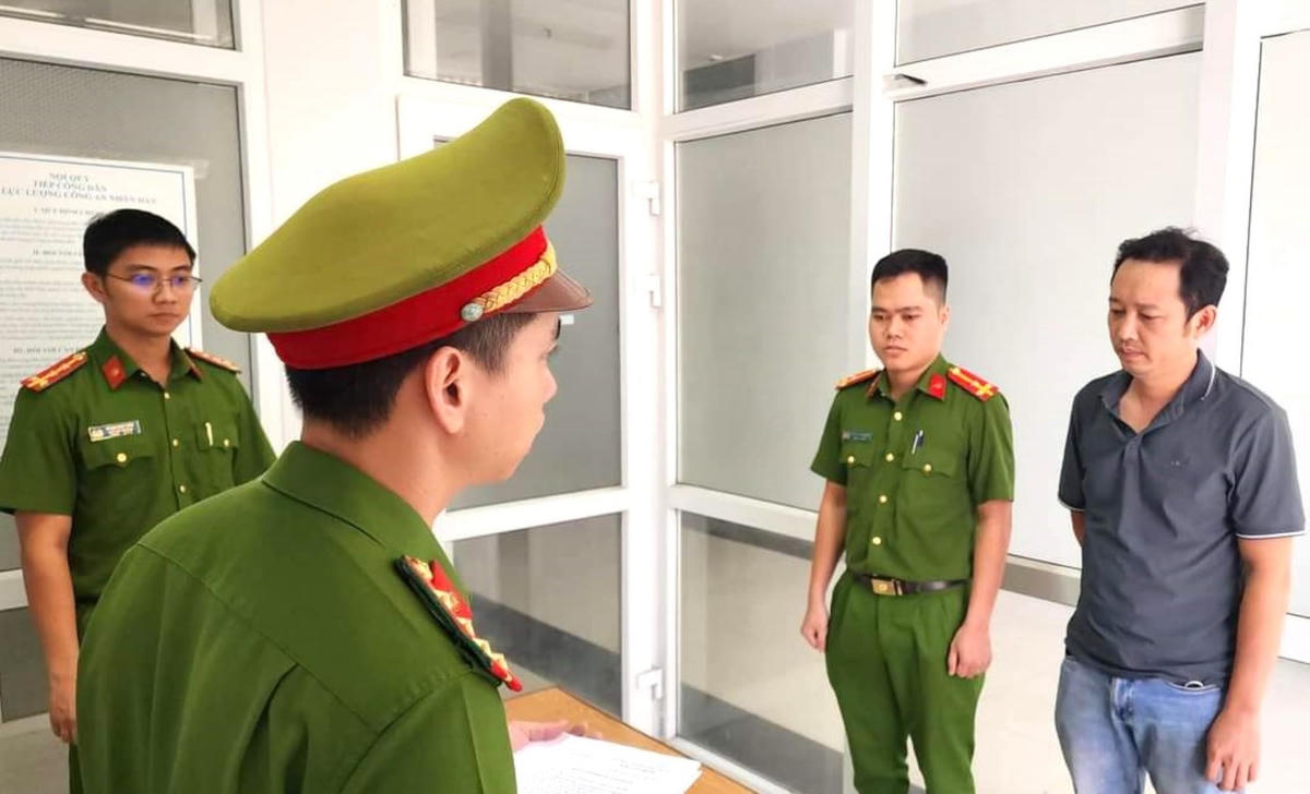Lâm Học (áo xanh đen, bên phải) nghe công an đọc lệnh khởi tố, bắt giam. Ảnh: Công an Đà Nẵng.
