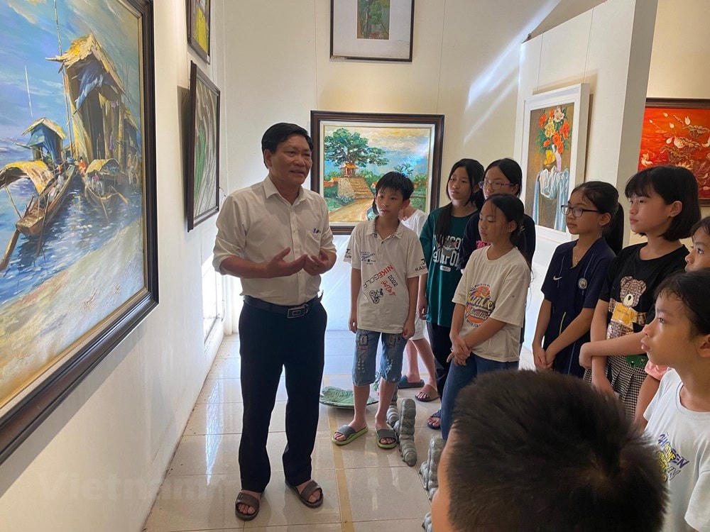 Họa sĩ Hoàng Tuấn Việt, Hội viên hội Mỹ thuật Việt Nam, Chủ nhiệm Câu lạc bộ Mỹ thuật Cổ Đô giới thiệu với các em về những bức tranh được trưng bày tại Bảo tàng Mỹ thuật Cổ Đô. (Nguồn: Vietnam+).
