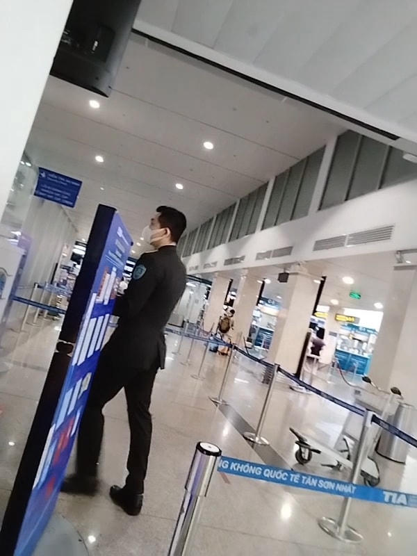 Một người mặc trang phục an ninh cảng hàng không quốc tế Tân Sơn Nhất dẫn hành khách không giấy tờ qua cửa an ninh. Ảnh: cắt từ clip.