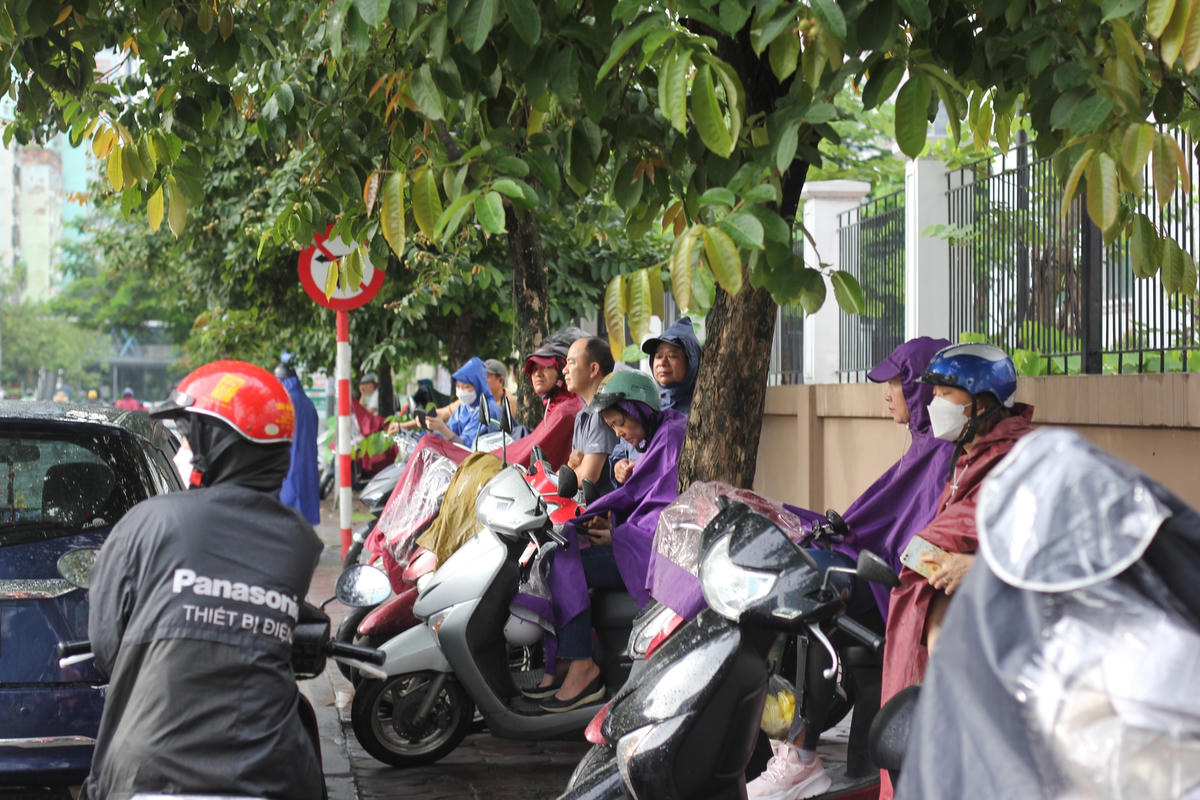 Thí sinh, phụ huynh và các tình nguyện viên tập trung ở trước cổng điểm thi THPT chuyên Amsterdam từ sáng sớm. Ảnh: Ngọc Ánh.