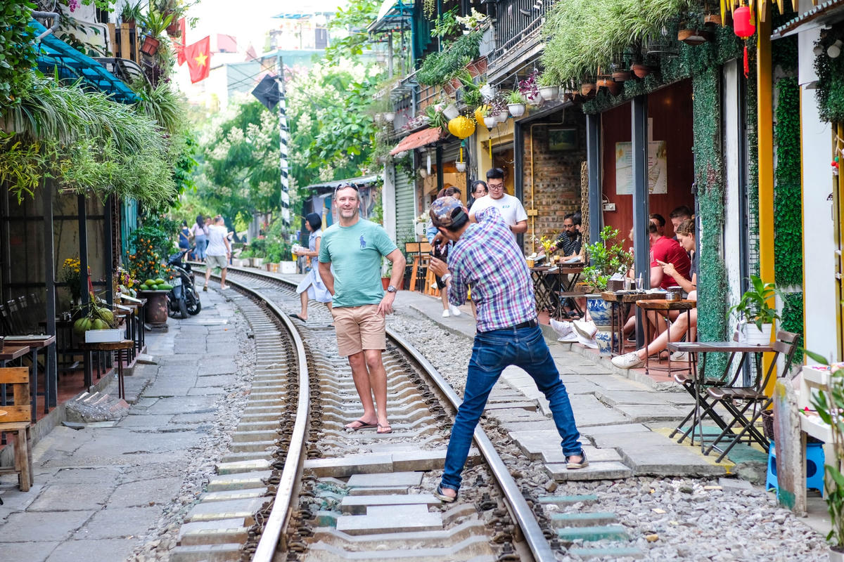 Có những khách du lịch ngồi hẳn xuống đường tàu để chụp hình.