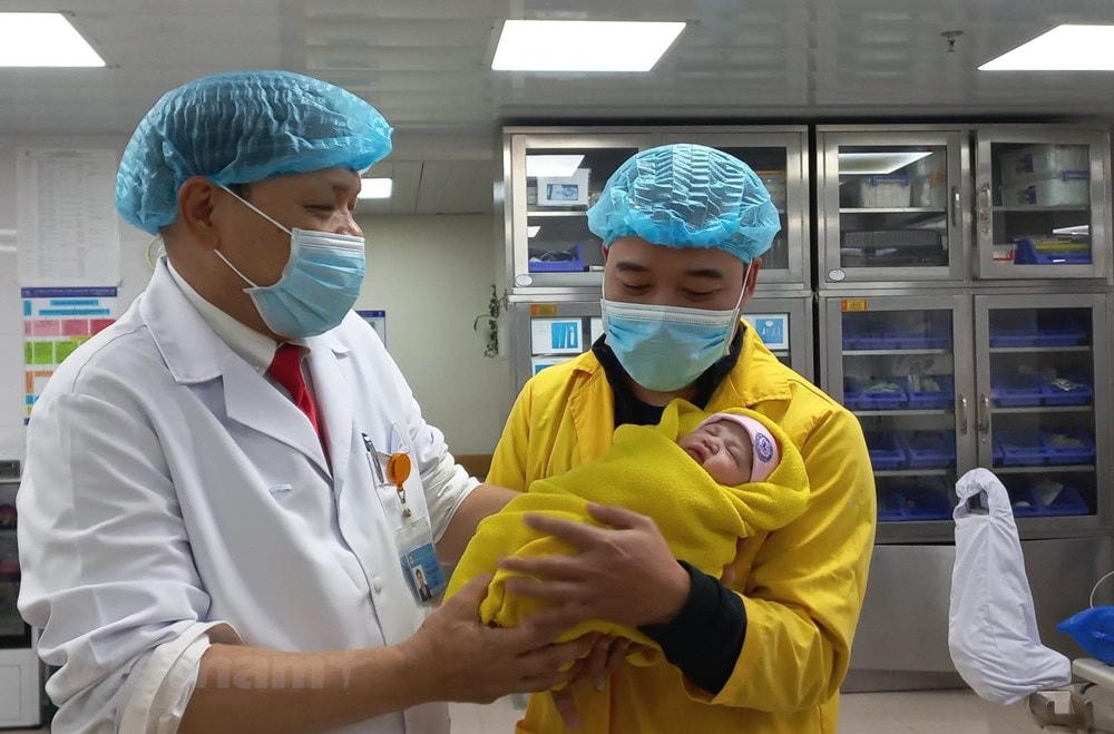 Phó giáo sư Trần Danh Cường - Giám đốc Bệnh viện Phụ sản Trung ương trao bé gái cho người bố. (Ảnh: T.G/Vietnam+).